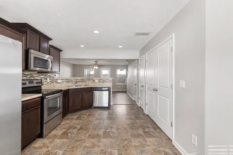 a large kitchen with stainless steel appliances granite countertop a refrigerator and a stove top oven