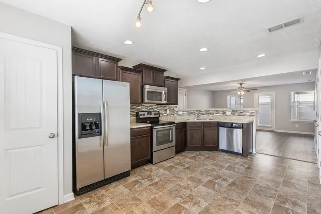a large kitchen with a refrigerator and a stove top oven