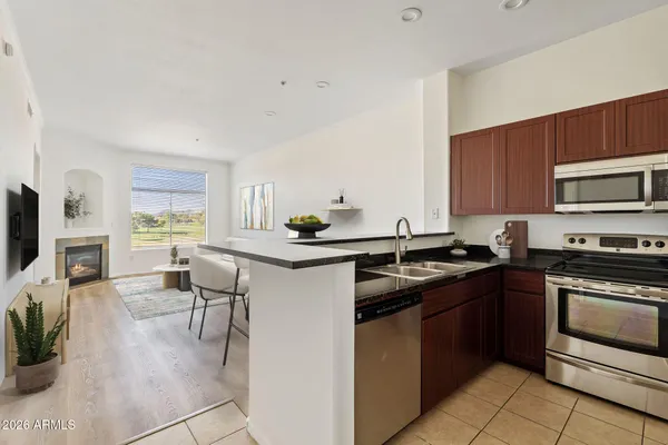 a kitchen with stainless steel appliances granite countertop a stove top oven a sink dishwasher a dining table and chairs with wooden floor