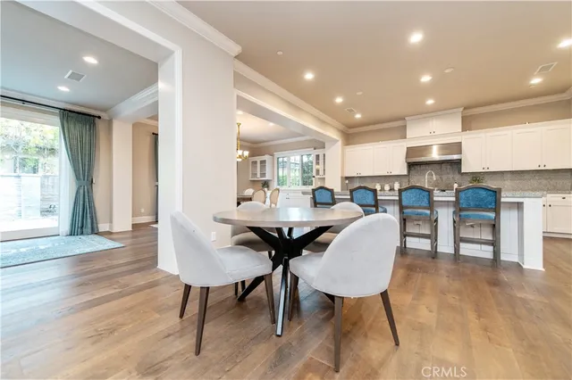 a kitchen with stainless steel appliances granite countertop a dining table chairs refrigerator and sink