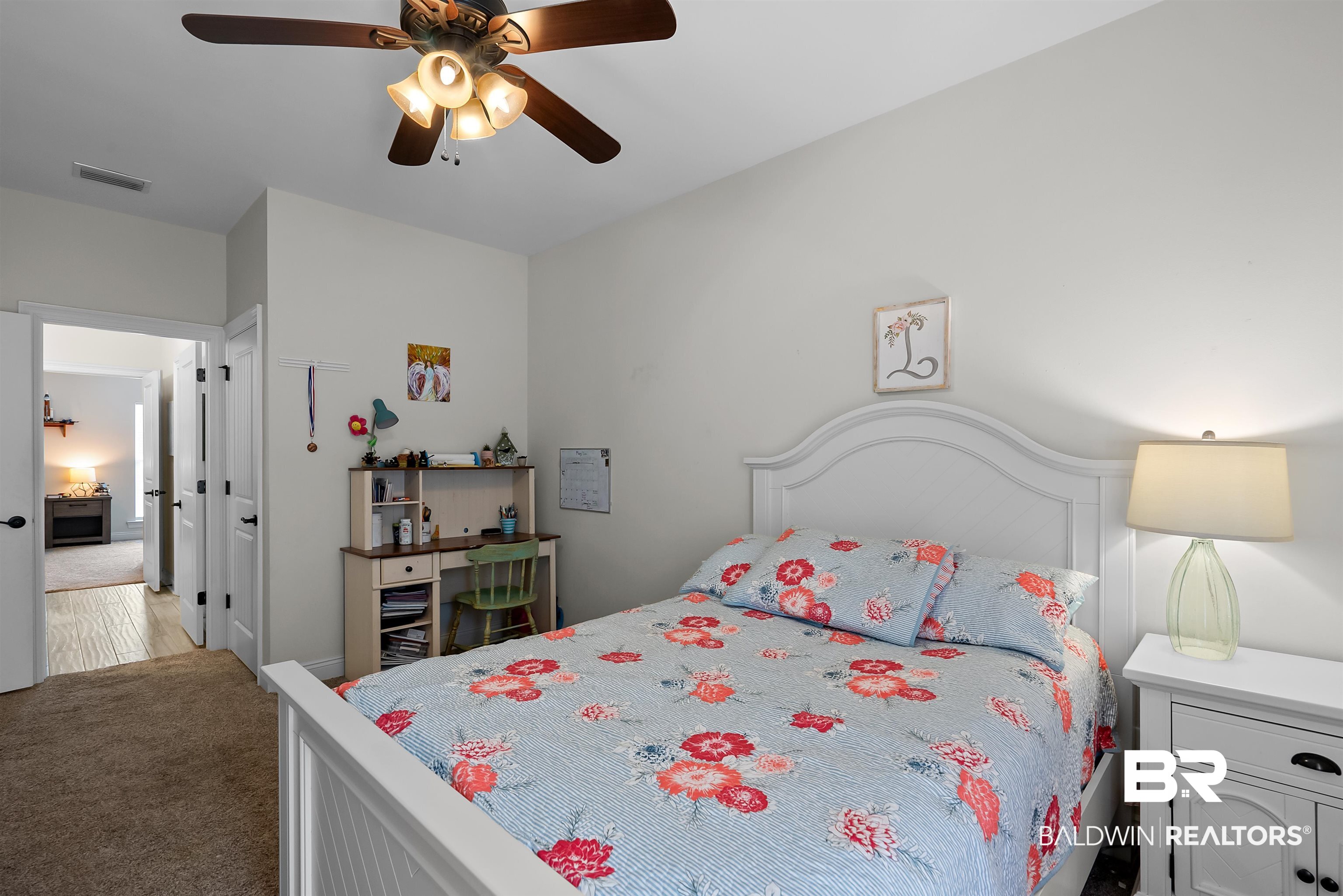 12070 Comalander Road Fairhope, AL 36532 - Photo 30 of 50 Bedroom featuring a wood-finish ceiling fan with integrated lighting, white walls, and a white paneled headboard