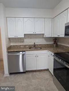 a kitchen with granite countertop white cabinets and a sink
