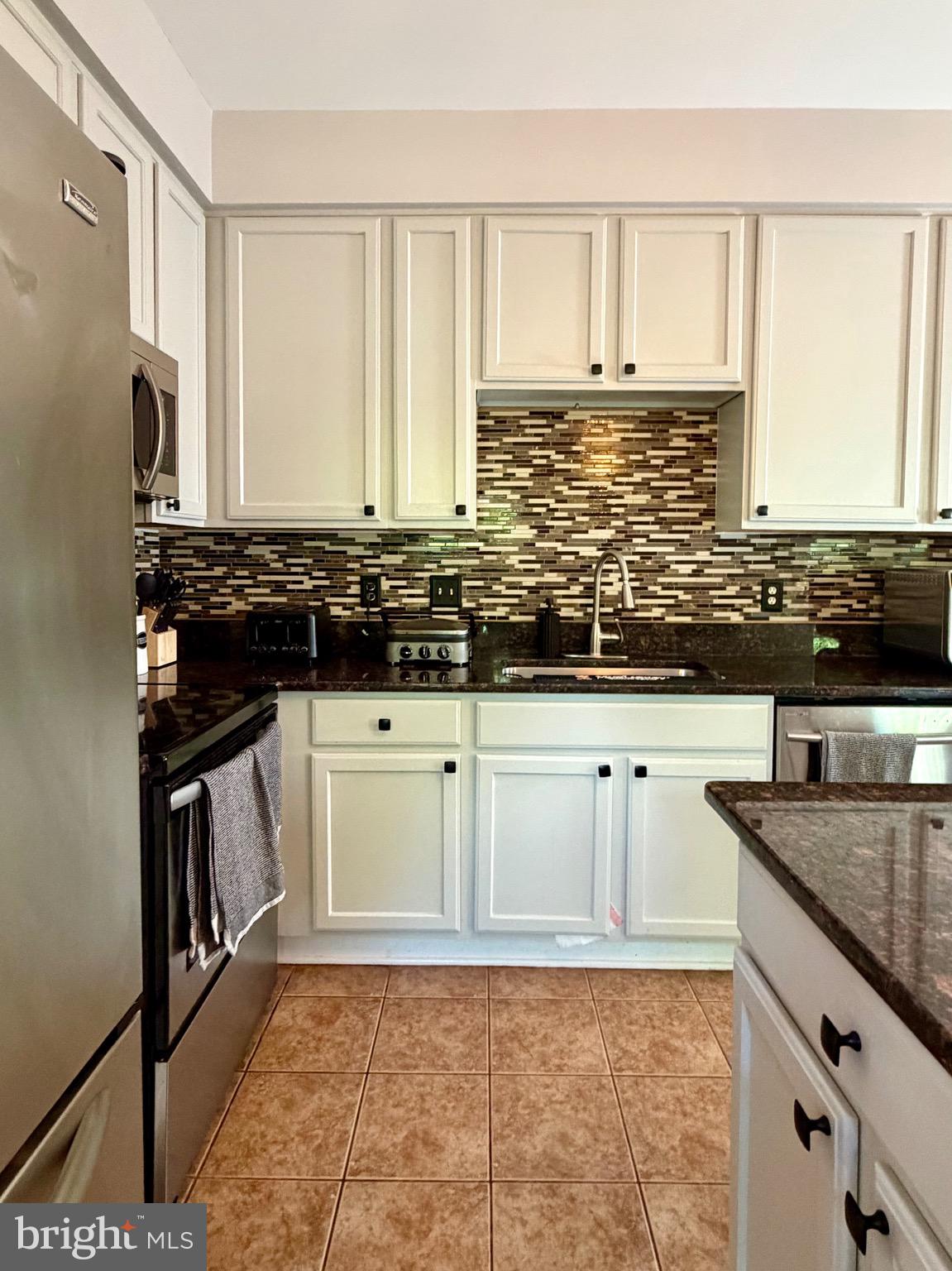 7108 Wheeling Way Gainesville, VA 20155 - Photo 11 of 45 a kitchen with stainless steel appliances granite countertop a stove a sink and white cabinets