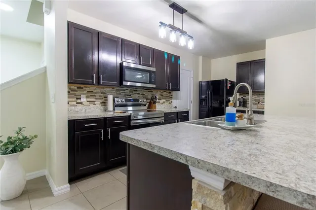 a kitchen with kitchen island granite countertop a sink stainless steel appliances and living room view
