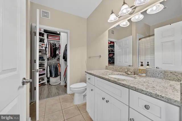 a bathroom with a granite countertop sink a toilet and a mirror