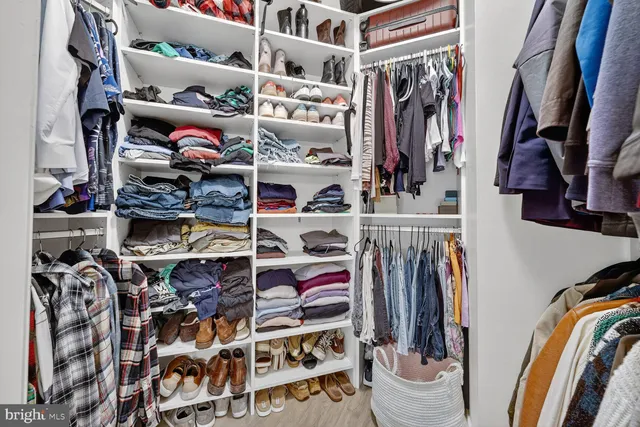 a view of walk in closet with clothes and shoes