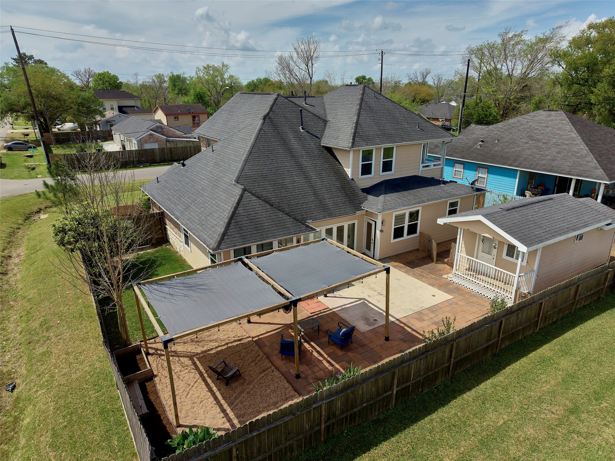 4219 Redbud Street Houston, TX 77051 - Photo 23 of 25 This photo showcases a spacious two-story home with a fenced backyard featuring a large patio area covered by a pergola and a detached structure, ideal for outdoor relaxation and entertaining.