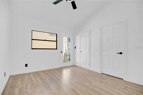 an empty room with wooden floor cabinet and windows