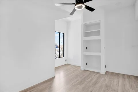 an empty room with windows and fan