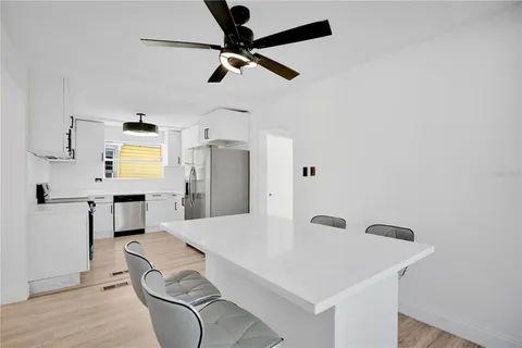 a kitchen with stainless steel appliances kitchen island a refrigerator sink and white cabinets