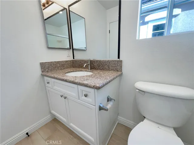 a bathroom with a granite countertop toilet sink and mirror