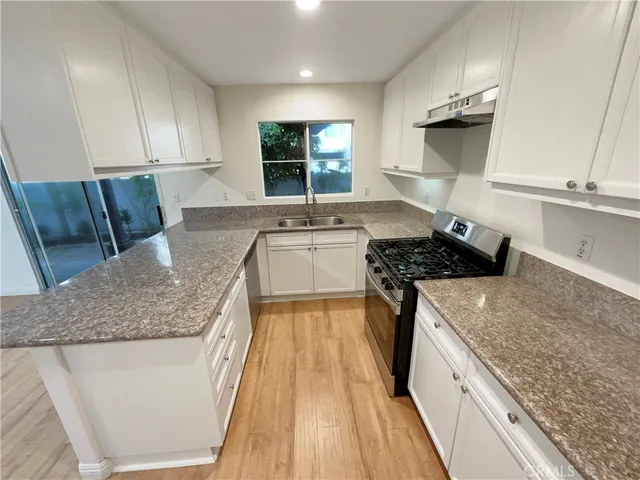 a kitchen with kitchen island granite countertop a sink stove and cabinets