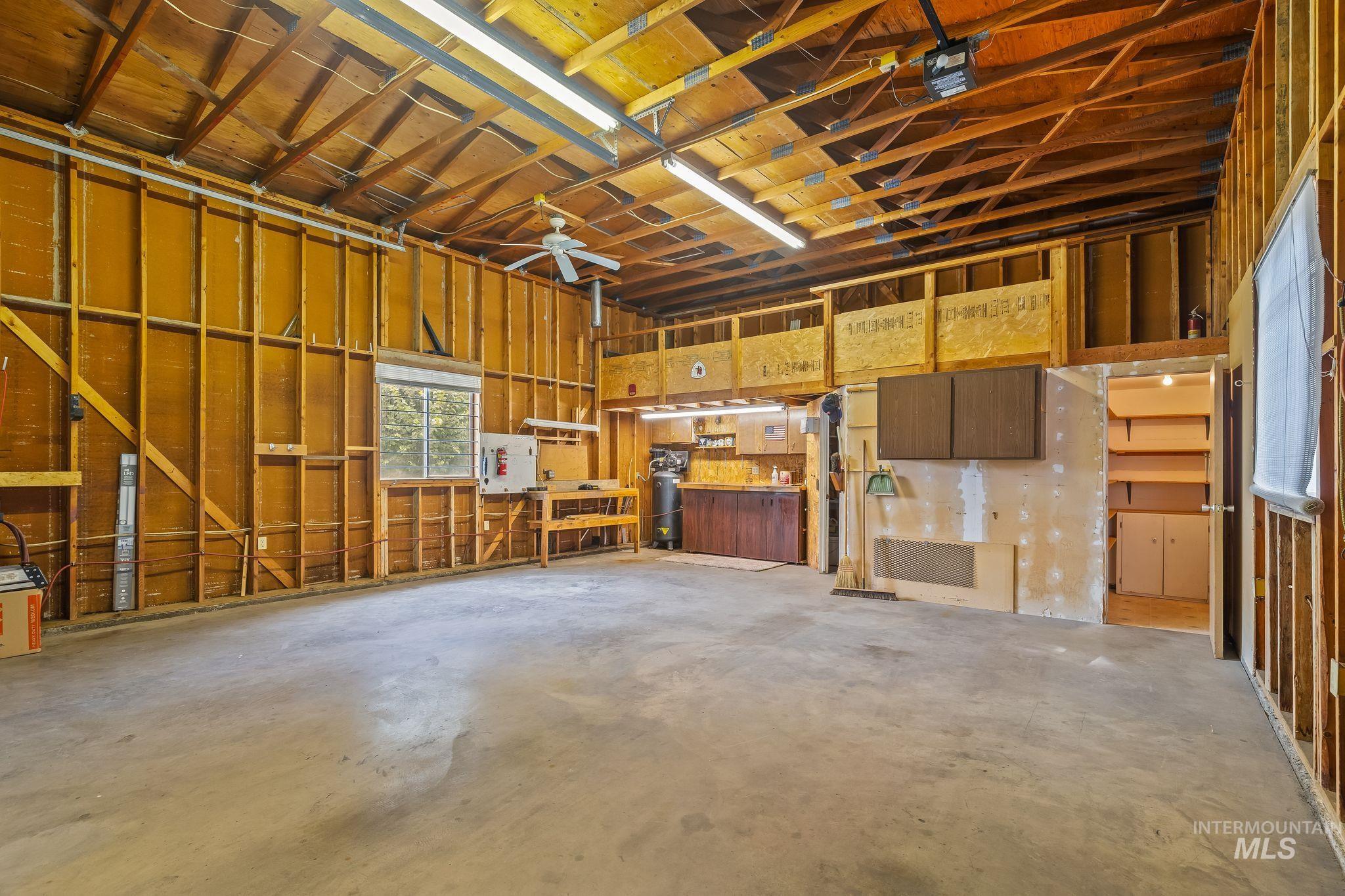 1721 3rd Street Lewiston, ID 83501 - Photo 24 of 45 Spacious garage interior featuring an exposed wood-beam ceiling, concrete flooring, and a ceiling fan