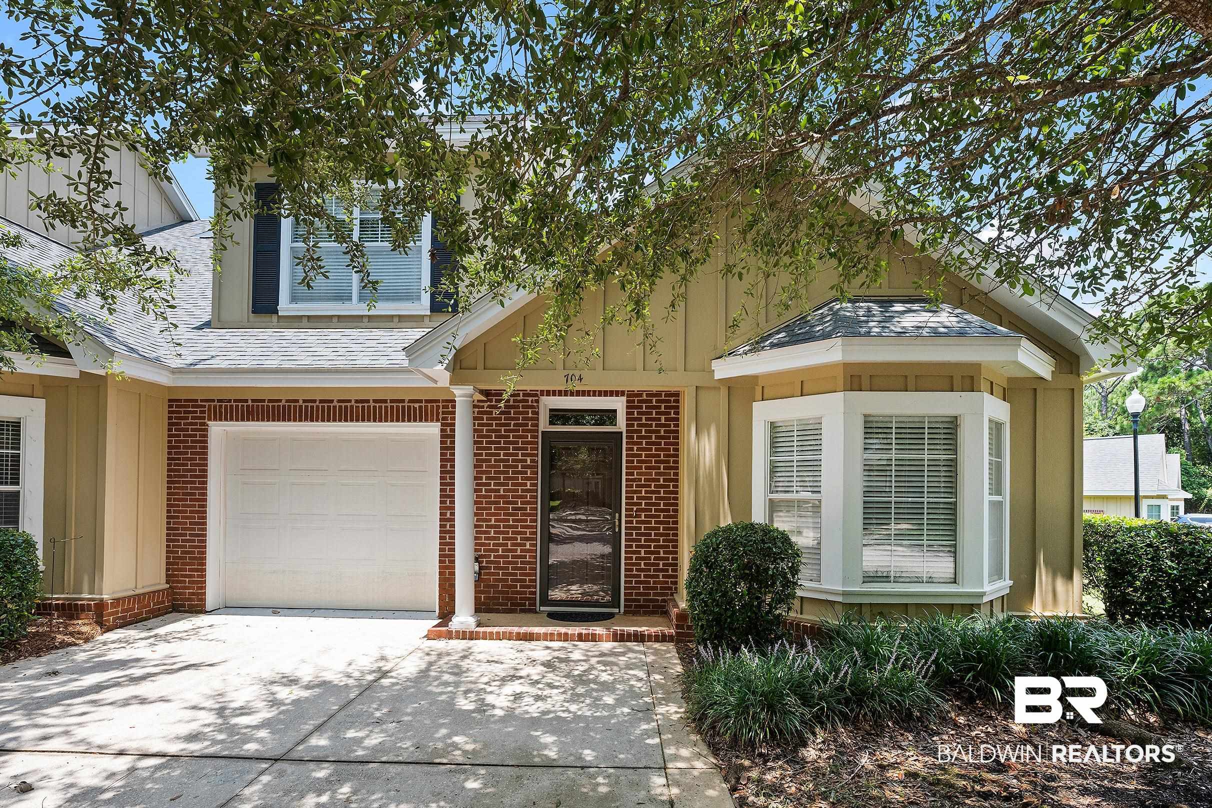 430 West Fort Morgan Road, Unit 704 Gulf Shores, AL 36542 - Photo 1 of 35 Exterior facade featuring brick accents, board and batten siding, a bay window with blinds, an attached garage, and a covered entry