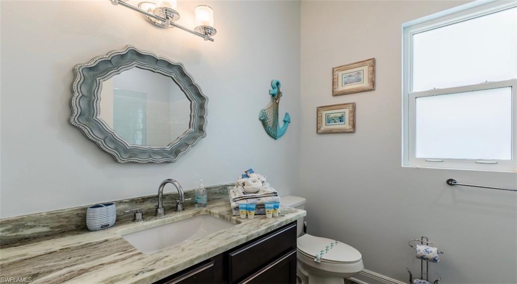 118 Bermuda Road Marco Island, FL 34145 - Photo 11 of 16 a bathroom with a granite countertop toilet a sink and a mirror