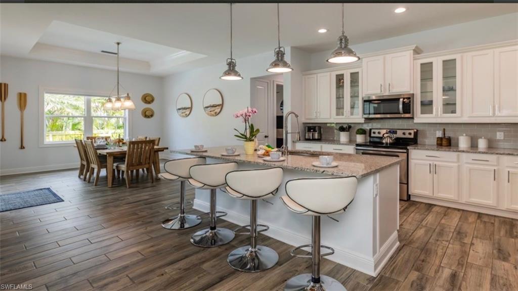 118 Bermuda Road Marco Island, FL 34145 - Photo 6 of 16 a kitchen with stainless steel appliances granite countertop a stove a sink a dining table and chairs with wooden floor