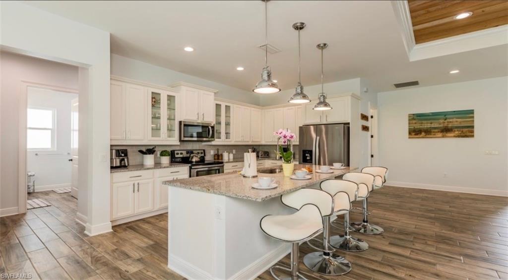 118 Bermuda Road Marco Island, FL 34145 - Photo 7 of 16 a kitchen with stainless steel appliances kitchen island granite countertop a sink a stove a dining table and chairs with wooden floor