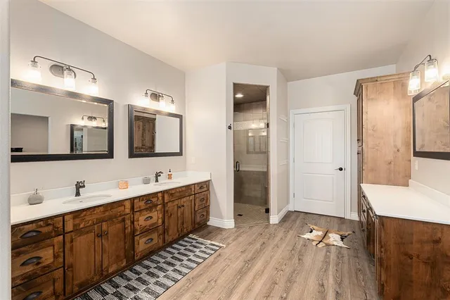 a spacious bathroom with a double vanity sink a mirror and a shower