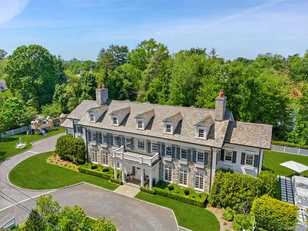 an aerial view of a house with yard and trees in the background