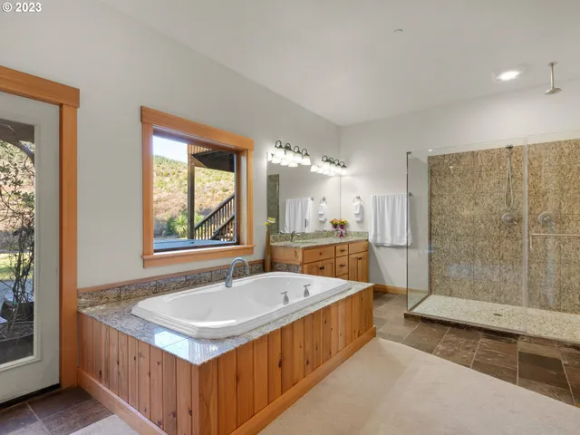 a bathroom with a tub a sink and large window