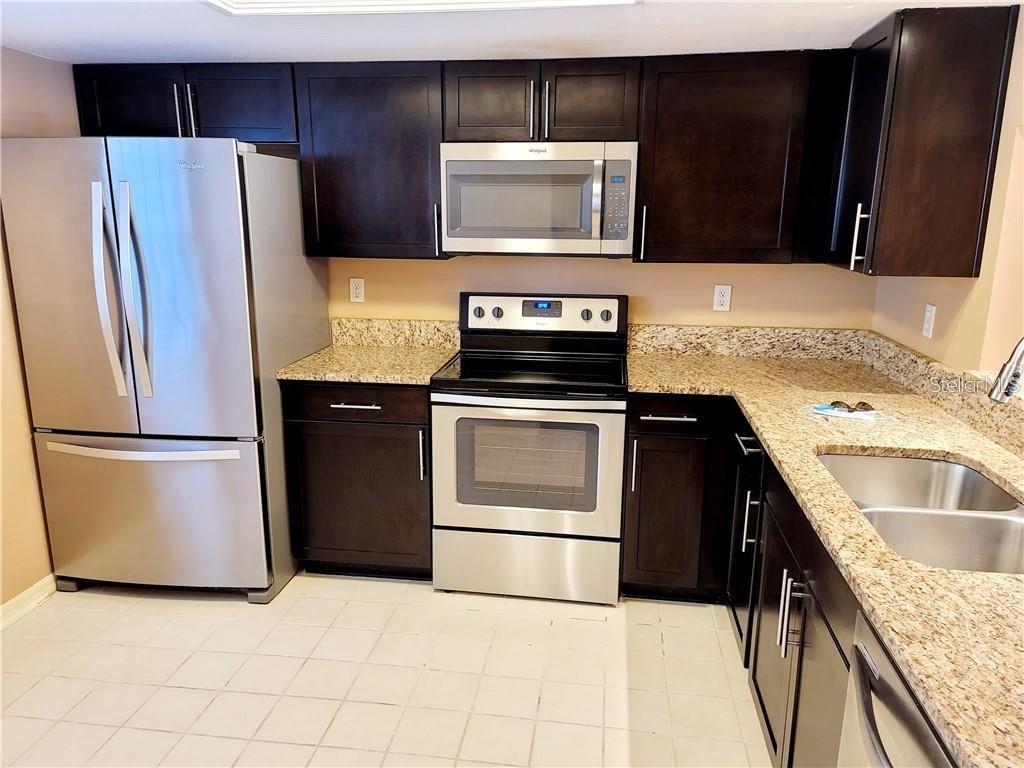 2163 Elm Street, Unit 803 Dunedin, FL 34698 - Photo 6 of 15 a kitchen with granite countertop a refrigerator stove and microwave