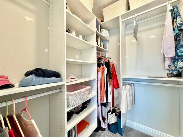 a view of walk in closet with clothes and shoes