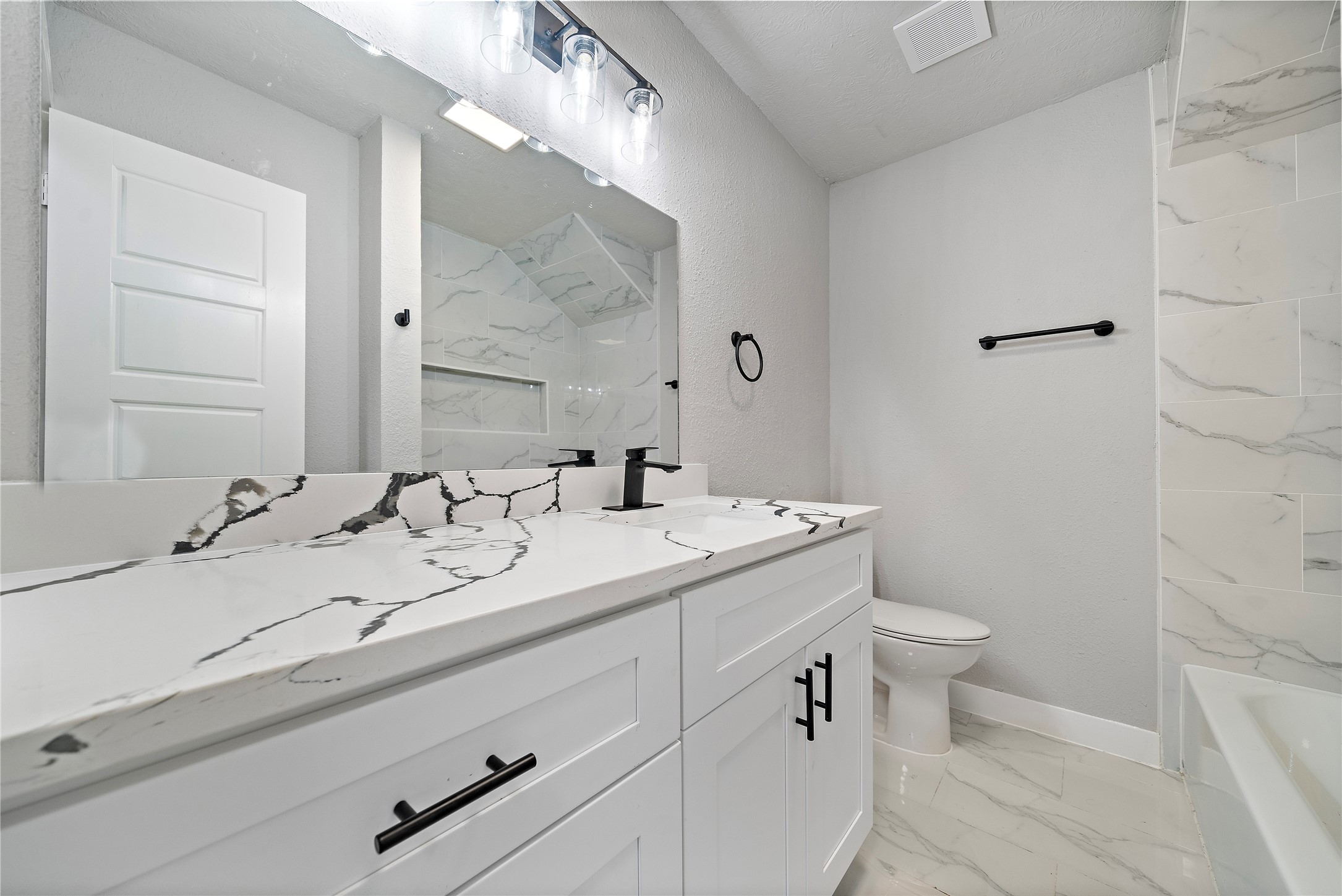 1004 West Harris Avenue Pasadena, TX 77506 - Photo 12 of 16 a bathroom with a double vanity sink toilet and a mirror