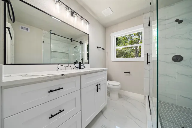 a bathroom with a double vanity sink a toilet and a shower