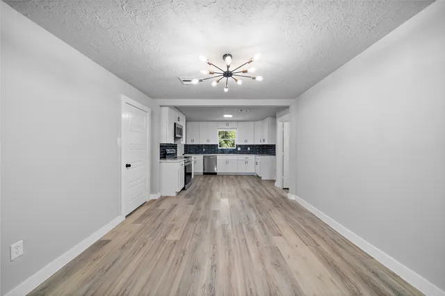 a view of a kitchen with a sink a refrigerator a ceiling fan and wooden floor