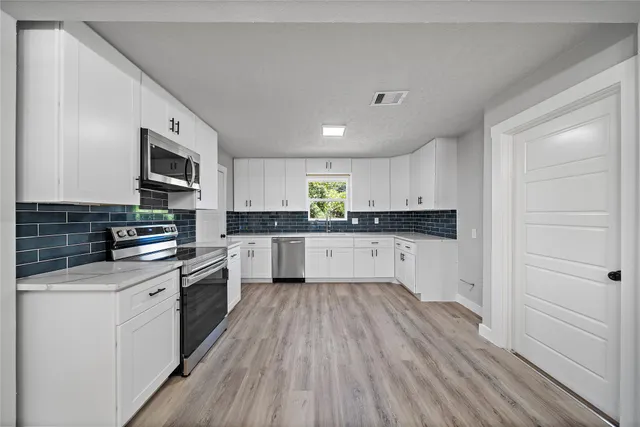 a kitchen with granite countertop a stove top oven a sink dishwasher and a refrigerator