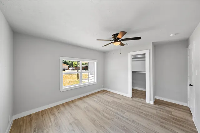 a view of empty room with wooden floor and fan