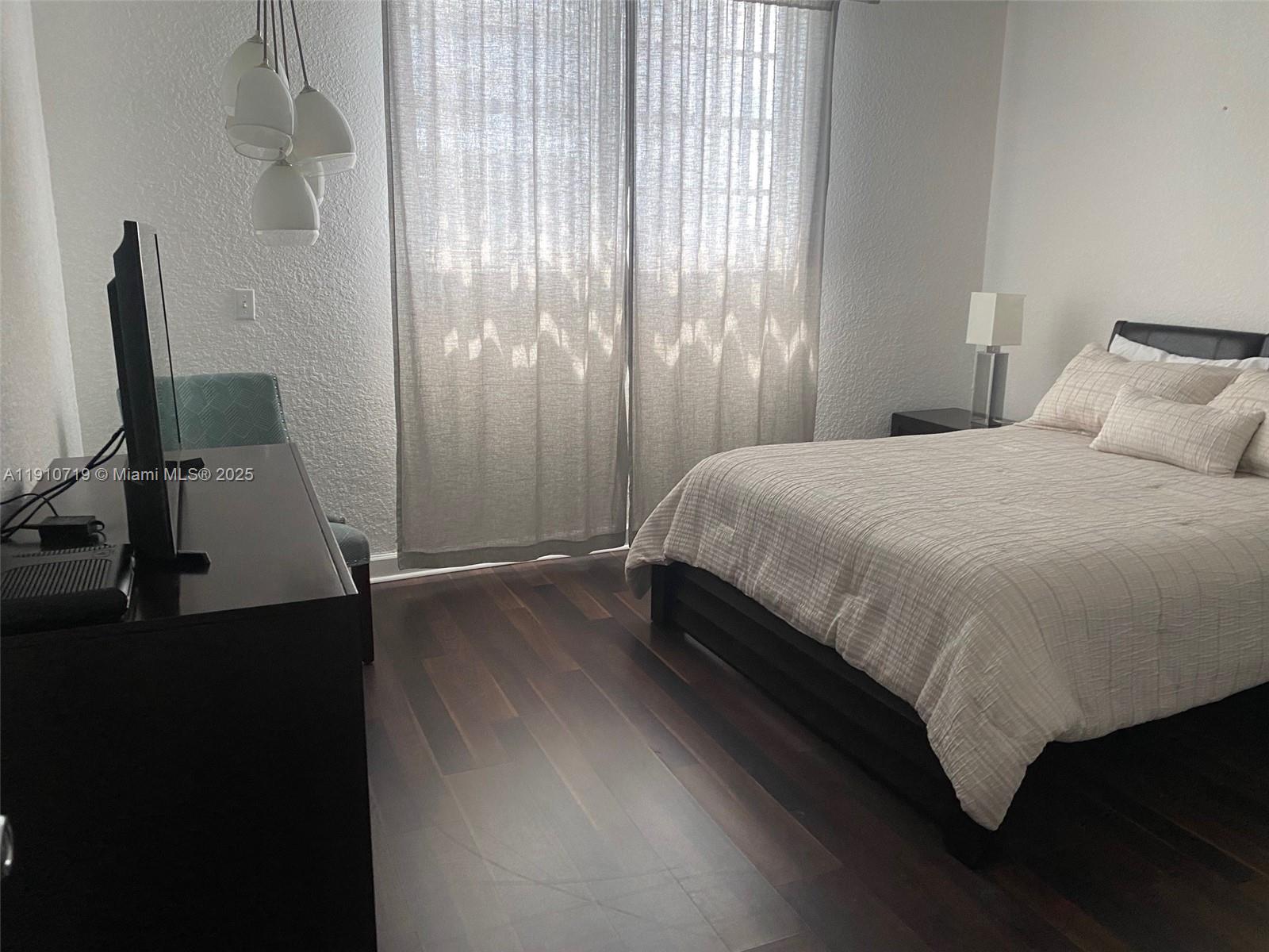 4001 South Ocean Drive, Unit 14F Hollywood, FL 33019 - Photo 11 of 16 a bedroom with a bed tv and wooden floor