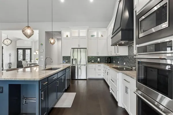 a large kitchen with stainless steel appliances and chandelier