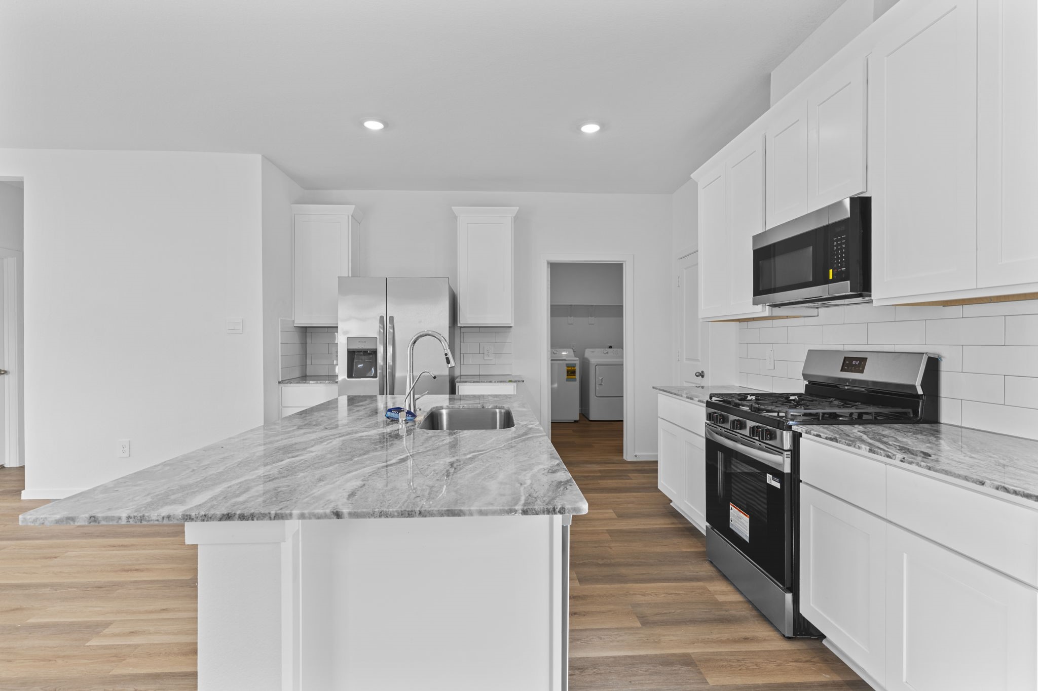 9019 Rose Water Iowa Colony, TX 77583 - Photo 9 of 44 a kitchen with stainless steel appliances granite countertop a stove top oven a sink and white cabinets