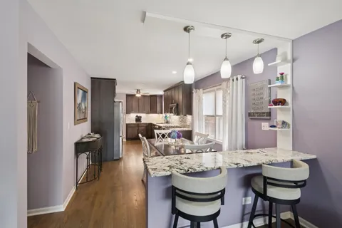 a kitchen with a refrigerator a sink dishwasher a dining table and chairs with wooden floor