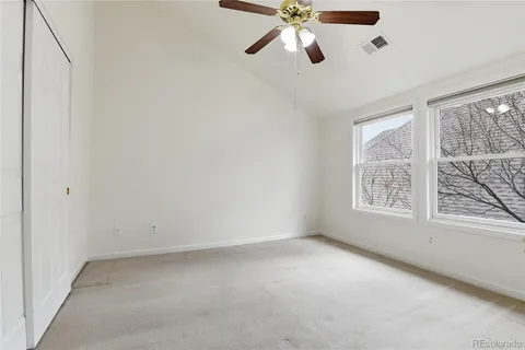 an empty room with windows and fan
