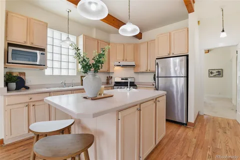 a kitchen with a refrigerator a sink cabinets and wooden floor