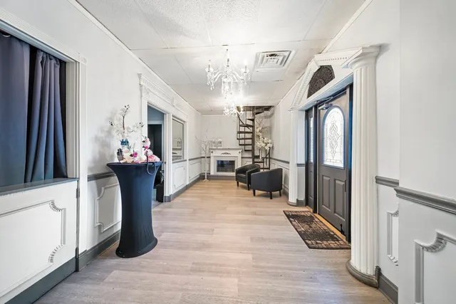 a view of a hallway with a dining table a chandelier and a mirror
