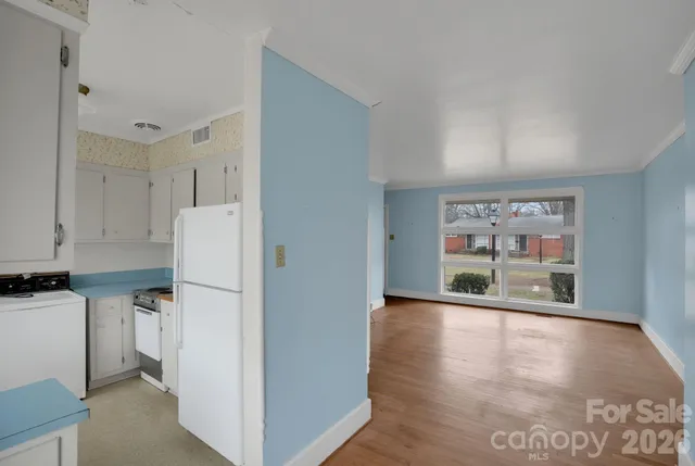 a view of a kitchen with refrigerator and wooden floor