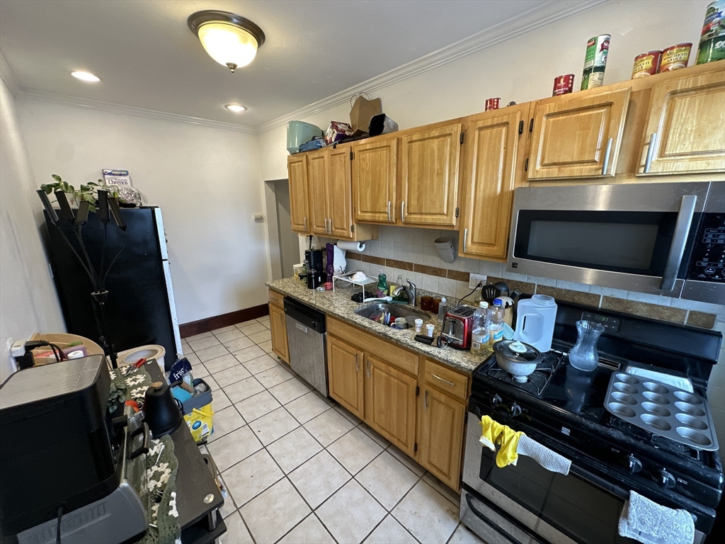 435 Walnut Avenue, Unit 8 Boston, MA 02119 - Photo 7 of 12 a kitchen with stainless steel appliances a stove refrigerator sink and microwave