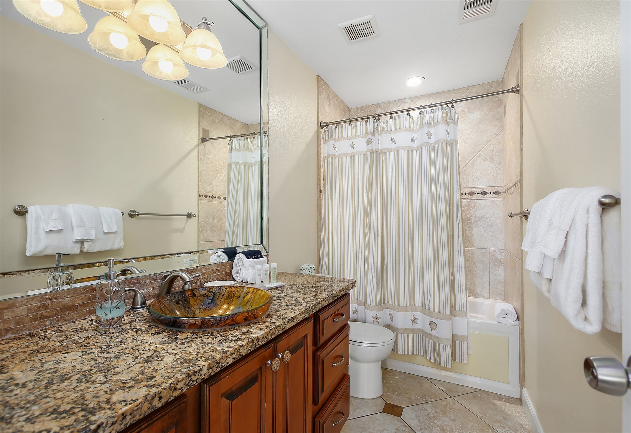 10811 Termini-San Luis Pass Road, Unit 2112 Galveston, TX 77554 - Photo 15 of 22 a bathroom with a granite countertop sink a toilet and a tub