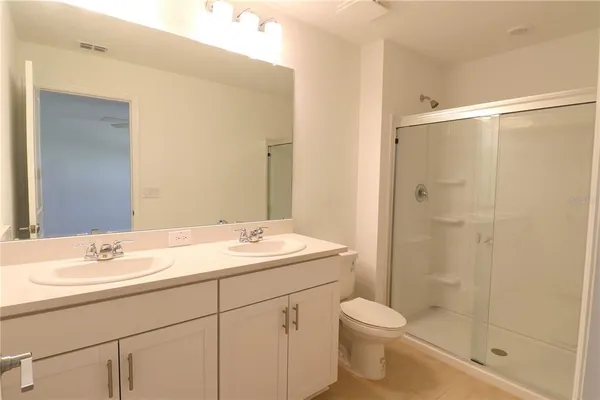 a bathroom with a shower sink vanity mirror and toilet