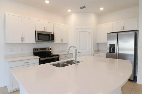 a kitchen with stainless steel appliances a stove a sink a refrigerator white cabinets and a refrigerator