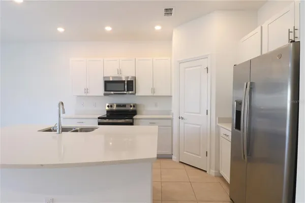 a kitchen with stainless steel appliances granite countertop a refrigerator a stove and a sink