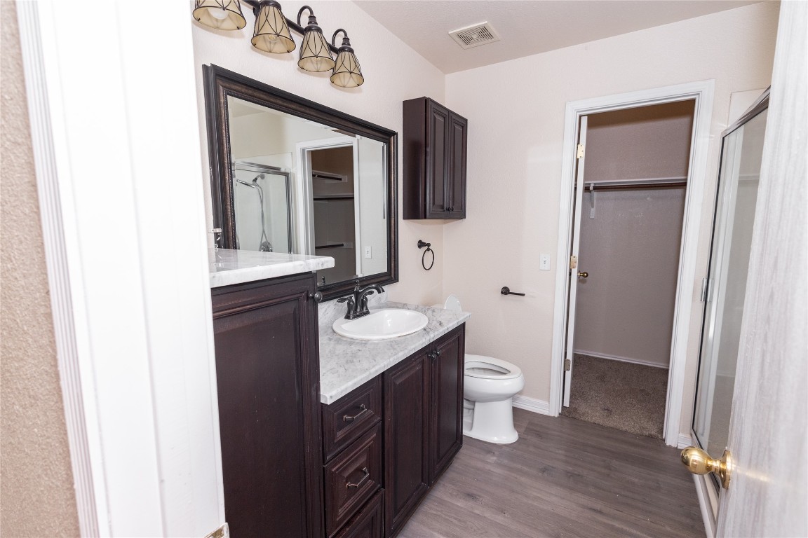 184 Unity Kyle, TX 78640 - Photo 15 of 33 Bathroom with a shower stall, vanity, dark wood-style floors, and a walk in closet