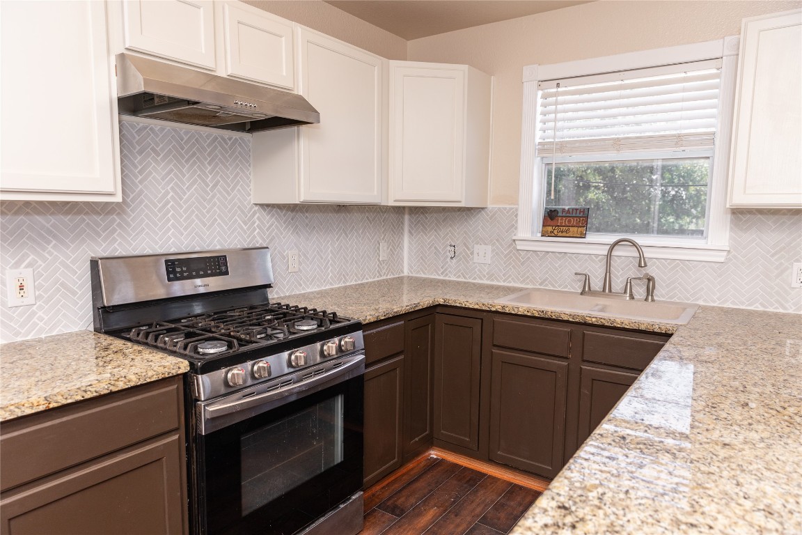 184 Unity Kyle, TX 78640 - Photo 2 of 33 Kitchen with stainless steel gas range oven, backsplash, under cabinet range hood, and white cabinetry