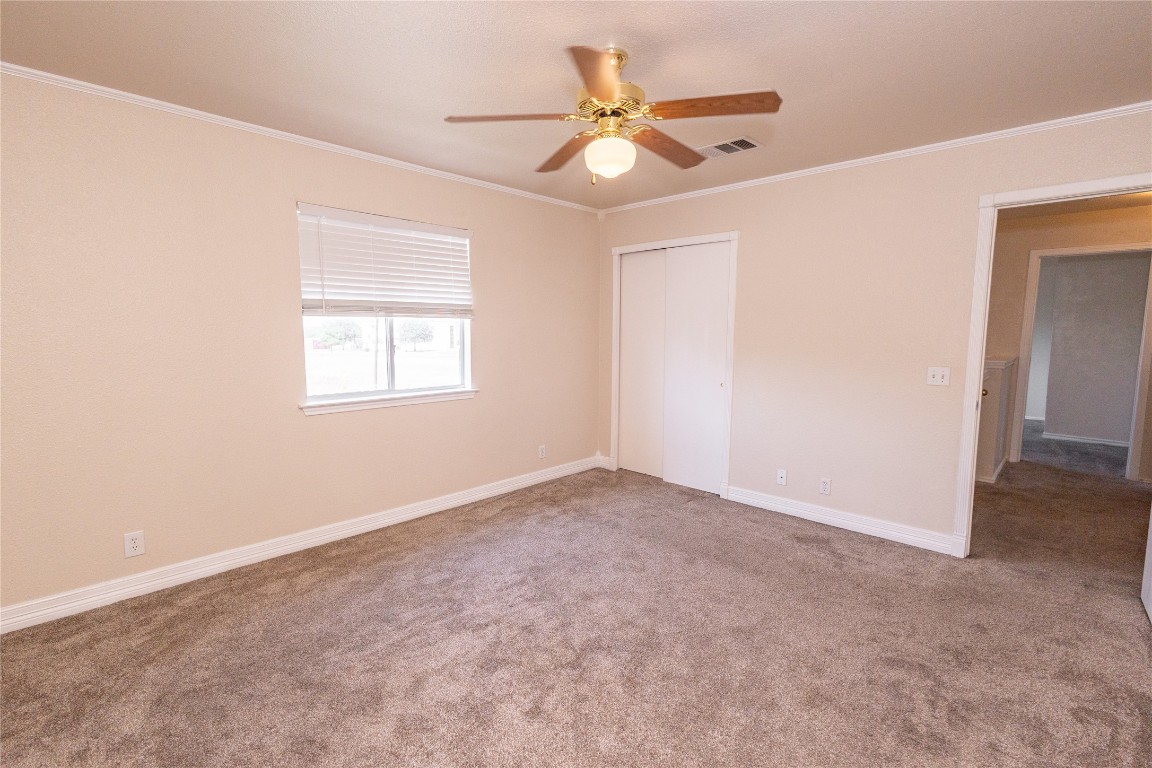 184 Unity Kyle, TX 78640 - Photo 23 of 33 Unfurnished bedroom with crown molding, light colored carpet, a ceiling fan, and a closet