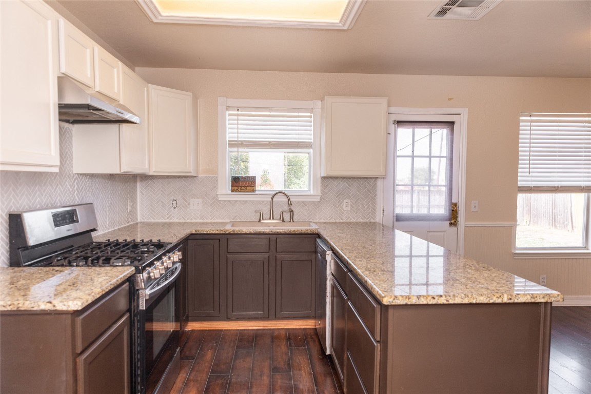 184 Unity Kyle, TX 78640 - Photo 3 of 33 Kitchen featuring stainless steel appliances, a peninsula, dark wood finished floors, tasteful backsplash, and light stone counters