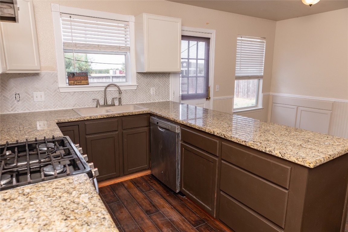184 Unity Kyle, TX 78640 - Photo 4 of 33 Kitchen featuring a wainscoted wall, dishwasher, backsplash, light stone counters, and dark wood finished floors