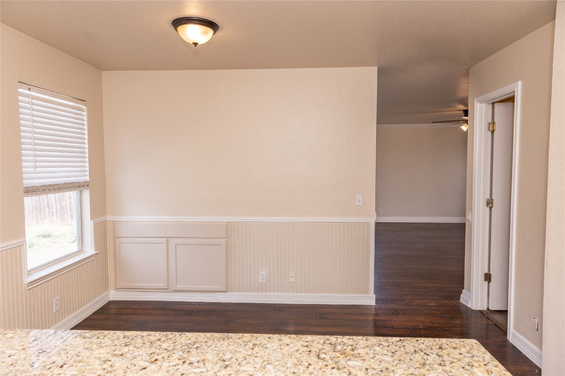 184 Unity Kyle, TX 78640 - Photo 6 of 33 Unfurnished room featuring dark wood-style floors, wainscoting, and a ceiling fan